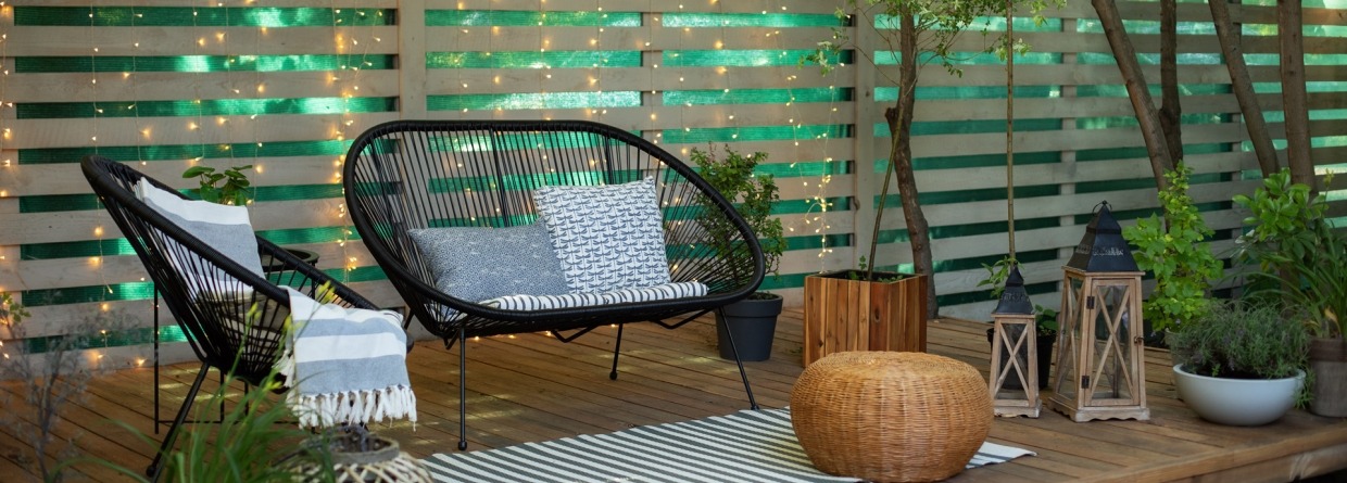 Terras met houten vlonders en een houten schutting met mooie tuinmeubels